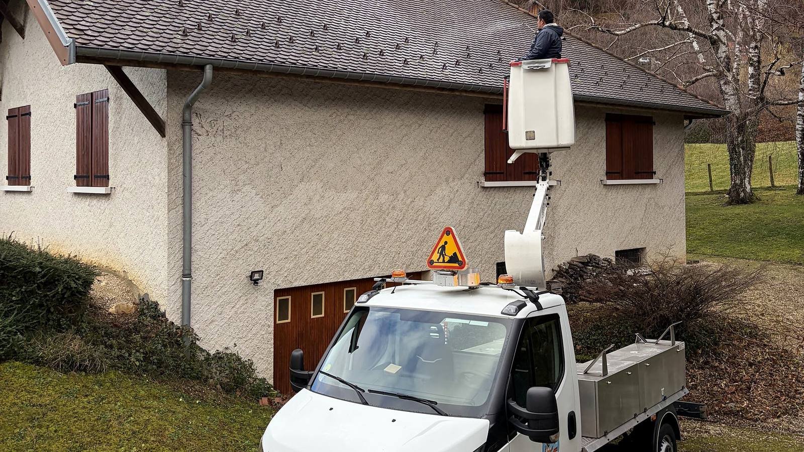Camion nacelle et ouvrier devant une maison pour intervenir sur la toiture