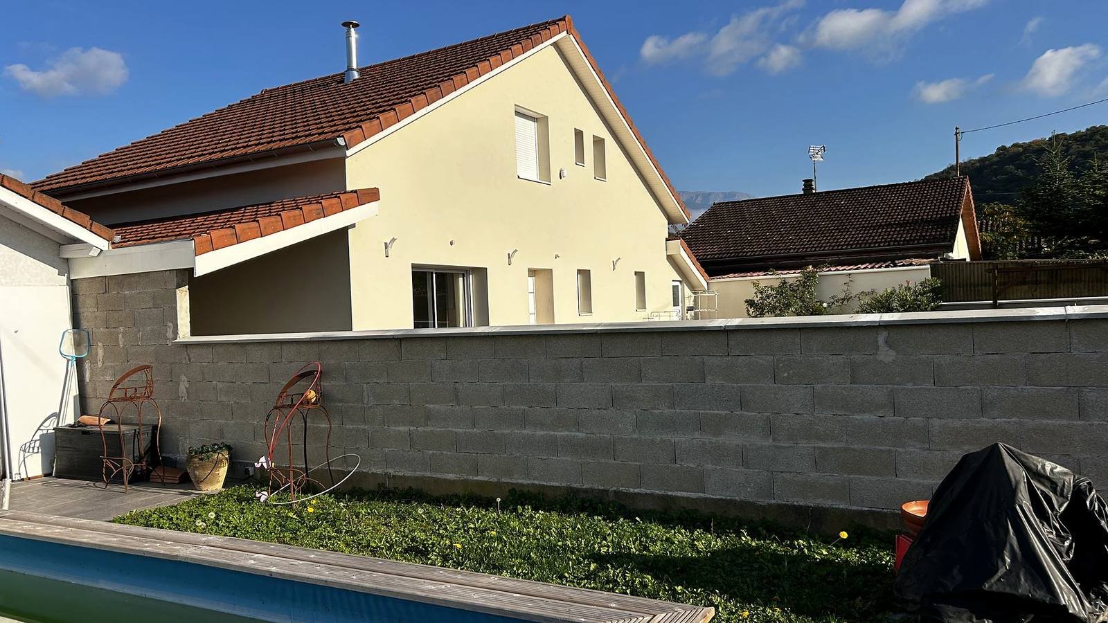 Maison crépie jaune à toiture en tuiles rouges, avec piscine