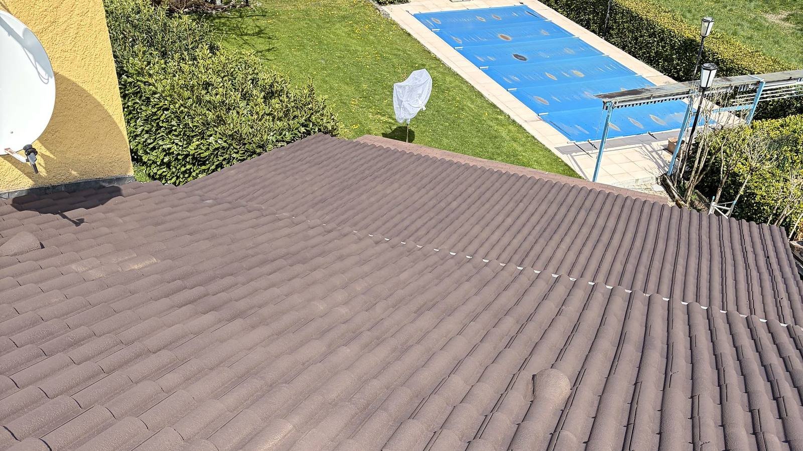 Toiture en tuiles brunes au-dessus d'un jardin avec piscine